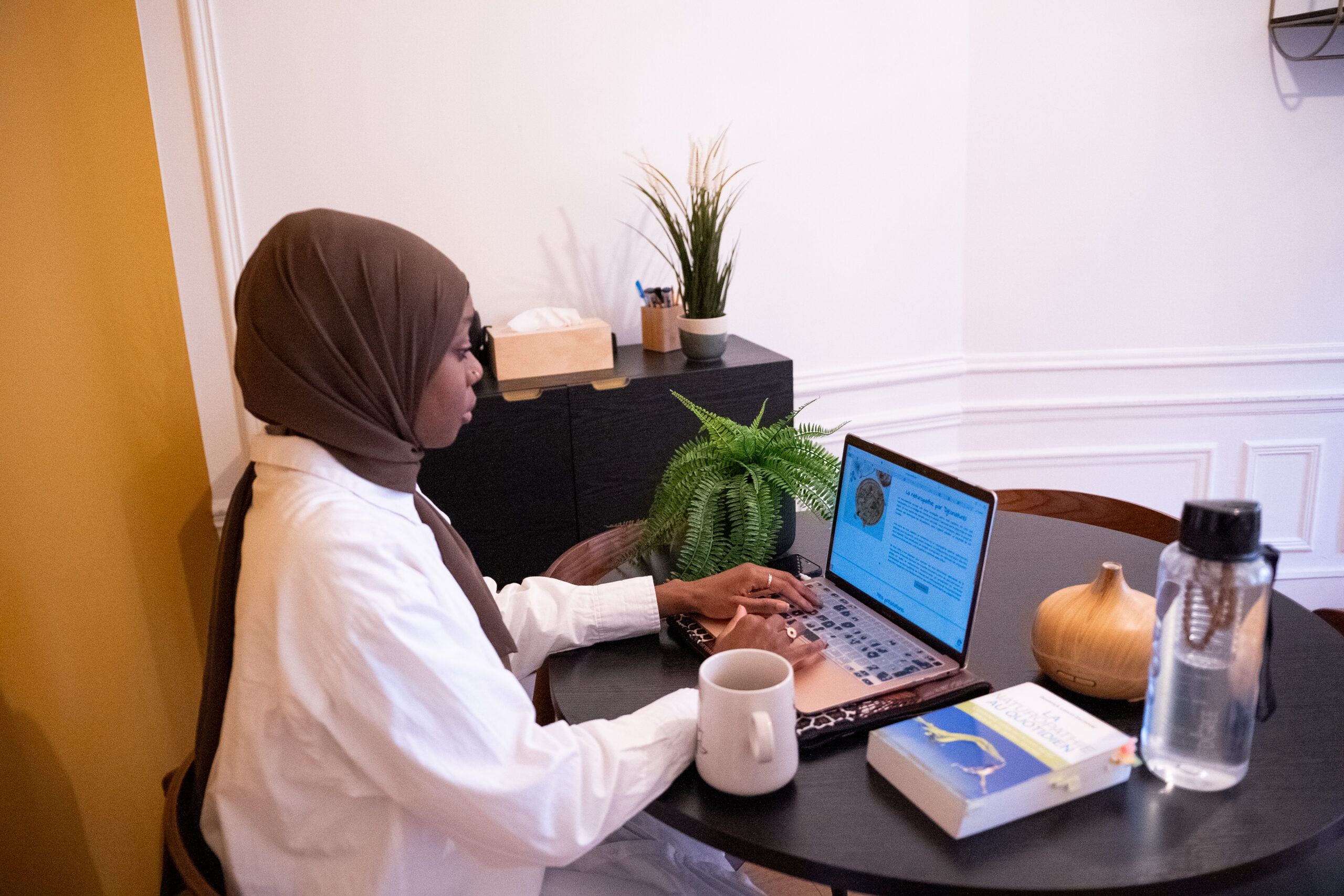 Djeonaturel, naturopathe spécialisée dans l'accompagnement des sportifs, travaillant sur son ordinateur dans son bureau.